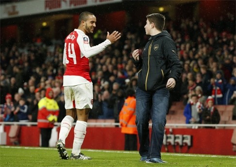 Arsenal's Theo Walcott shakes hands with a fan before giving him his shirt on the pitch after the game. Photo: Reuters