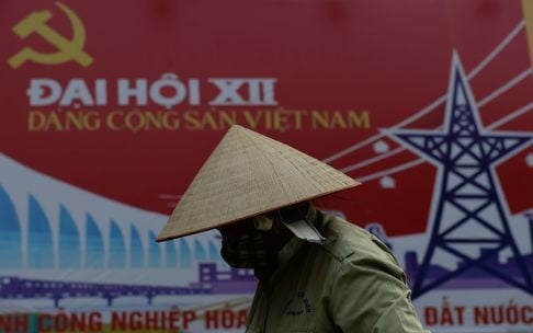 A woman tends flowers in front of a billboard spruiking the up-coming national congress of the ruling Vietnam Communist Party to choose its next leaders. Photo: AFP