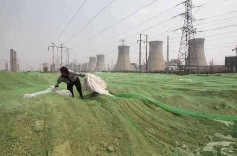 A labourer collects plastic bags on a dust screen covering construction waste near a power plant in Zhengzhou, Henan province in this July 15, 2014 file photo. Photo: Reuters