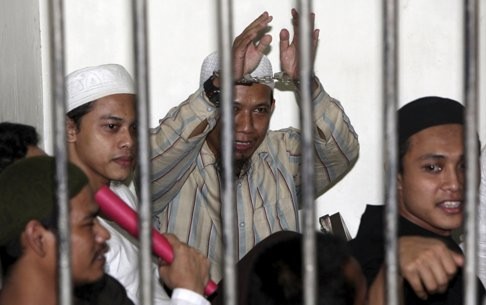 Radical Muslim cleric Aman Abdurrahman, also known as Oman Rochman, raises his hands in a holding cell as he waits with other militants for their trial in Jakarta, in August, 2010. From behind bars, Abdurrahman heads an umbrella organisation formed in 2015 through an alliance of splinter groups that support Islamic State. Photo: Reuters