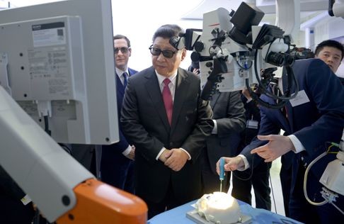 Chinese President Xi Jinping is joined by British Chancellor of the Exchequer George Osborne (face obscured) as they don 3D glasses during a demonstration of medical equipment for a presentation by the Hamlyn Centre for Robotic Surgery at Imperial College London on October 21, 2015. Photo: AFP