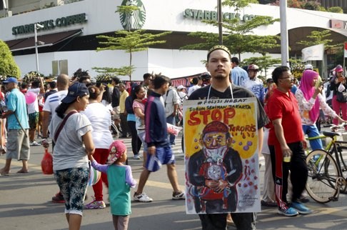 A man holds a placard that reads “Stop Terrorists” at the site of the militant attack in central Jakarta. Photo: Reuters