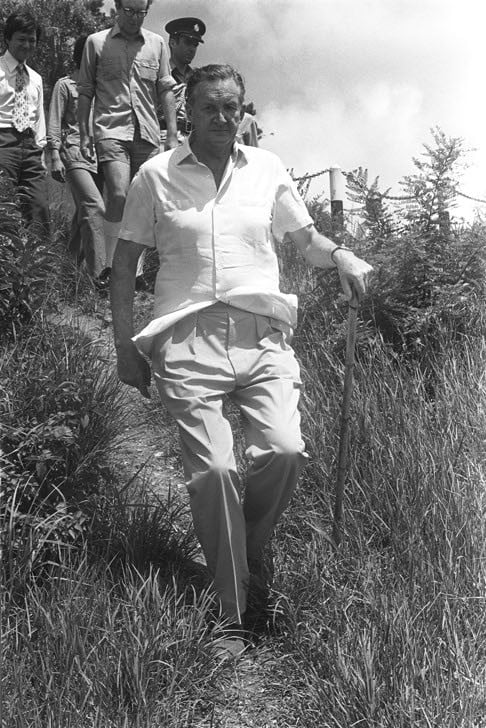 Governor Murray MacLehose walking down a slope to visit a youth leadership training camp in Tai Po in 1976.