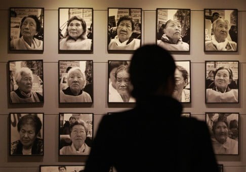 A visitor looks at portraits of former “comfort women” at the House of Sharing, a nursing home and museum for former sex slaves in Toechon, South Korea. Photo: AP