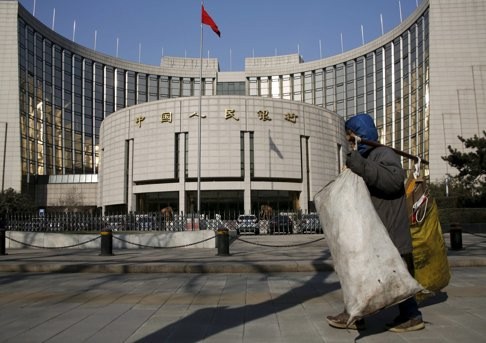 A garbage collector walks past the headquarters of the People's Bank of China in Beijing. Photo: Reuters