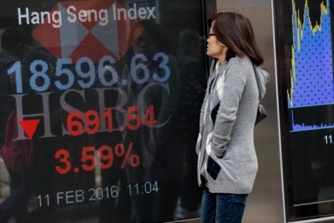 A woman looks at an electronic billboard displaying the Hang Seng Index numbers in Hong Kong. The market slumped 3.8 percent in the morning as markets reopened following a three-day trading break, headed for their worst start to a lunar new year since 1994 . Photo: EPA