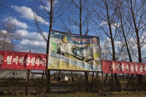A billboard along the train tracks in Rajin, North Korea, reads “Let’s work toward opening a new phase for constructing a powerful economy with the mentality and spirit to conquer the universe”. Photo: AP