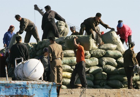 North Koreans load goods destined for China on the waterfront of the North Korean town of Sinuiju, on the Chinese border. Photo: AP