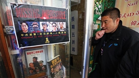 A visitor at Causeway Bay Books, where a poster on the window shows the missing booksellers. Photo: SCMP