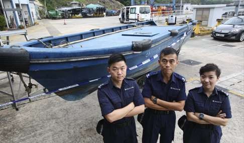 Police pose with the boat used for smuggling at a media briefing on illegal immigrants being smuggled into Hong Kong from South East Asia in Chek Lap Kok. Photo: SCMP