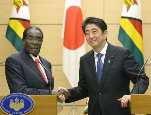 Mugabe and Abe shake hands after a joint press conference. Photo: Kyodo