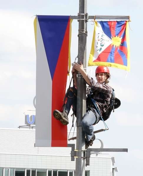 A video grab shows an activist replacing a Chinese flag on a lamp post with a Tibetan one. Photo: AP