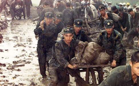 Chinese soldiers carry sandbags to strengthen the banks of a river in Hubei province during the massive floods of 1998. Photo: AP