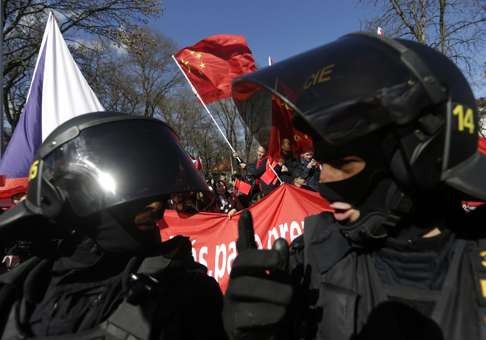 Riot policemen in Prague stand guard as they try to separate the supporters of visiting President Xi Jinping from the protesters demonstrating against China’s human rights abuses. Photo: AP