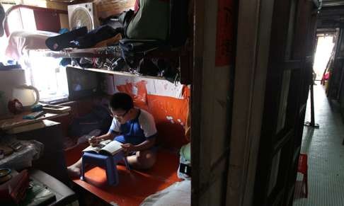 An eight-year-old boy does his homework in a subdivided apartment in Sham Shui Po. Photo: Dickson Lee