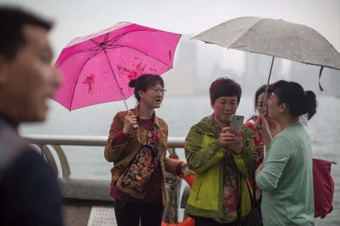 Mainland Chinese tourists chat in front of Victoria Harbour. Some 60 per cent of mainlanders surveyed claim to have received inferior treatment from service providers like retailers. Photo: EPA