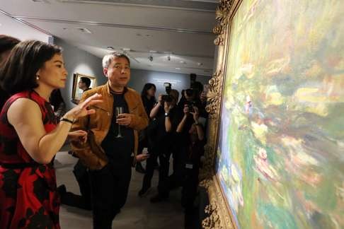 Rebecca Wei (left), president of Christie's Asia, stands alongside Chinese collector Liu Yiqian (centre) as they look at the painting Le Bassin aux nympheas by Claude Monet at the preview in Hong Kong. Photo: Dickson Lee