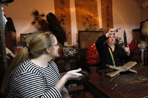 Tourists try out antique household objects collected by Wang Jinming at the Beijing Old Items Exhibition.