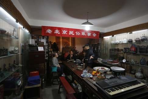 A tour guide shows tourists household items and street objects collected by Wang.