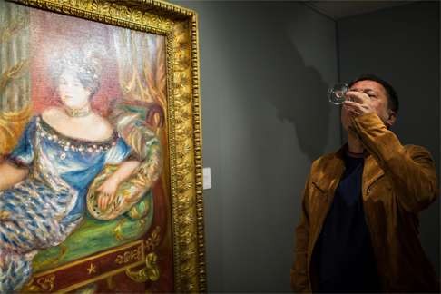 Liu Yiqian drinks champagne as he looks at an oil painting by French artist Pierre-Auguste Renoir at the opening of the Christie’s spring season in Hong Kong on March 31. Photo: AFP