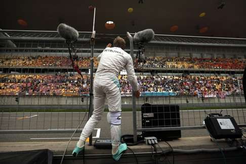 Nico Rosberg climbs the pit wall to wave to fans in the grand stand after the second practice session on Friday. Photo: AP