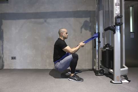 Resistance band assisted squat and hold. Photo: Jonathan Wong