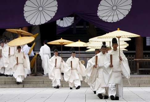 Shinto priests holding traditional umbrellas leave from the main Yasukuni shrine after a ritual to cleanse themselves during the annual Spring Festival. Photo: Reuters