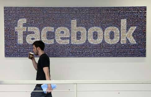 A Facebook employee walks past a sign at Facebook headquarters in Menlo Park, California. Photo: AP