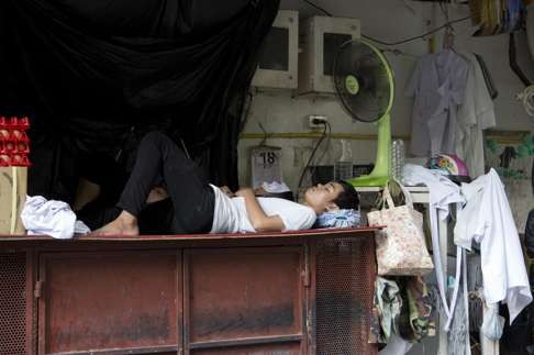 A restaurant naps under a fan during a break in central Bangkok, Thailand. Photo: AP