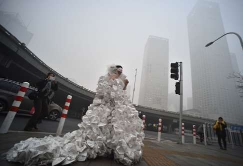 Artist Kong Ning wearing a wedding dress made up with 999 respirators while strolling along a Beijing street to call people's attention on environmental protection. Photo: Xinhua