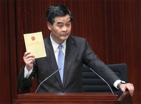 Chief Executive Leung Chun-ying holds up a copy of the Basic Law during a session in the Legislative Council. The central government has, practically, fulfilled its promise to Hong Kong, and the chief executive elections have been increasingly democratic. Photo: K. Y. Cheng