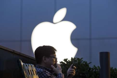 A man uses his mobile phone near a Apple store logo in Beijing, China, last week. Photo: AP