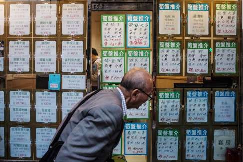 An elderly man inspects prices listed by a property agent. For millions of Hongkongers, being able to afford a roof over their heads is a lifelong struggle. Photo: Bloomberg