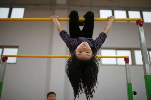 A young girl practises on the uneven bars in Shanghai. Photo: Reuters