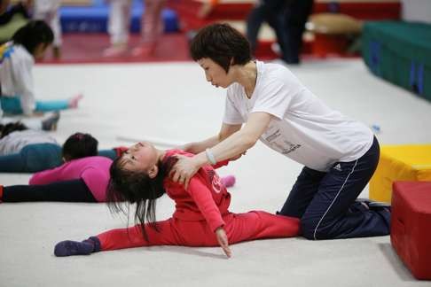 A coach helps a girl during gymnastics lessons at the Shanghai Yangpu Youth Amateur Athletic School in Shanghai. Photo: Reuters