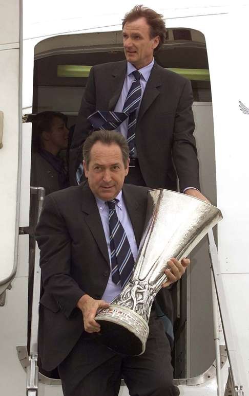Gerard Houllier walks down the plane steps with the Uefa Cup. Photo: Reuters