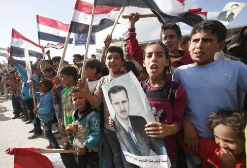 Local children with portraits of president Bashar al-Assad. Photo: EPA