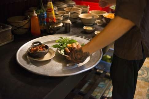 A waiter prepares to serve spring rolls at Secret Garden. Relaxed licensing laws and cheap rent makes Ho Chi Minh a maven of private kitchens.