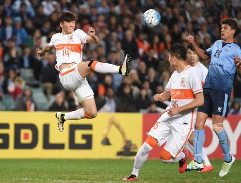 Shandong Luneng’s Wang Tong is airborne as he clears the ball. Photo: AFP