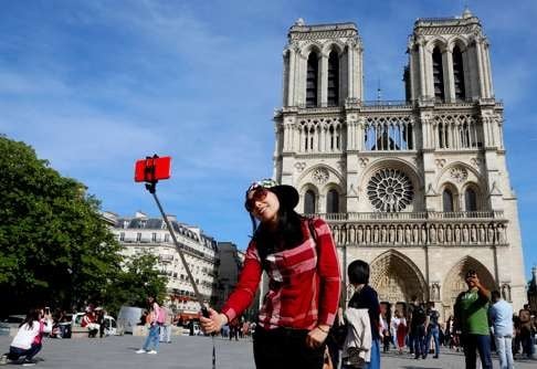 A Chinese tourist takes a selfie in front of Notre Dame Cathedral in Paris. Photo: Reuters