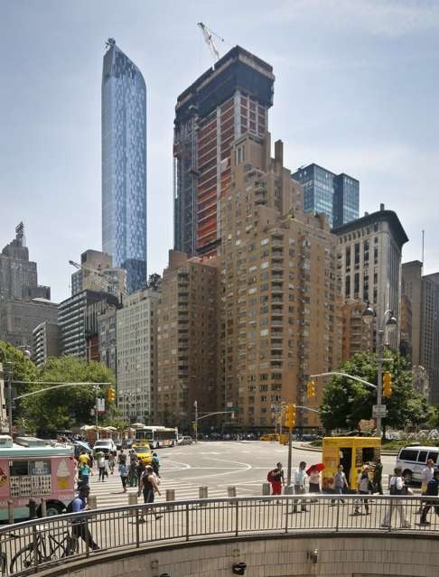 A luxury 90-floor apartment skyscraper “One57” left, rises above all other buildings overlooking Central Park, while a crane sits atop ongoing construction for a new condominium skyscraper at 220 Central Park South last week. Photo: AP