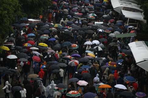 People amid a sea of umbrellas leave the Roland Garros stadium. Photo: AP