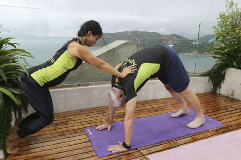 Root does the downward-facing dog yoga pose on his rooftop.