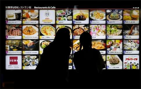 Women look at restaurant advertisement boards in central Tokyo. Like China, Japan’s dilemma is an internal debt issue of the left hand owing the right hand. Photo: Reuters