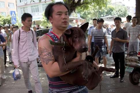 An animal activist carries a dog that he has bought to save it from being eaten during the festival in Yulin. Photo: AP