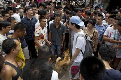 An animal rights activist (wearing the blue hat) is told to leave the market by dog sellers and locals in Yulin. Photo: AP