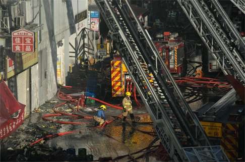 A firefighter walks in through a pool of water that has collected during efforts to put out a fire in the building in Ngau Tau Kok. Photo: AFP