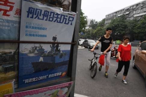 People walk past a military magazine featuring Chinese navy ships at a news stand in Beijing. Beijing must prepare for military confrontation in the South China Sea, state-run media said. Photo: AFP