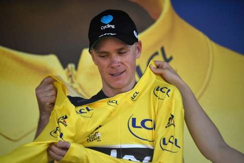 Chris Froome pulls on the overall race leader’s yellow jersey after winning the eighth stage. Photo: AFP