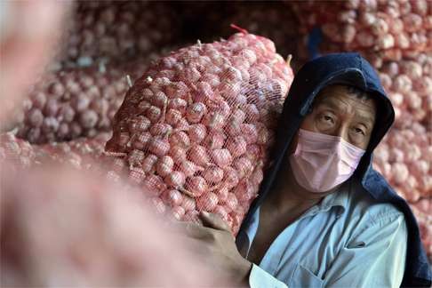 A migrant worker carries a bag of garlic at a garlic trade centre in Jinxiang county, Shandong province. China, the world’s largest socialist country, somehow now has the most billionaires, while migrant workers work in conditions that would never be acceptable in developed economies. Photo: Xinhua